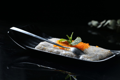 黑色背景上的一盘手打虾滑，上面放着鱼籽