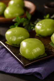 蓝色布背景上放着一碟小吃青团