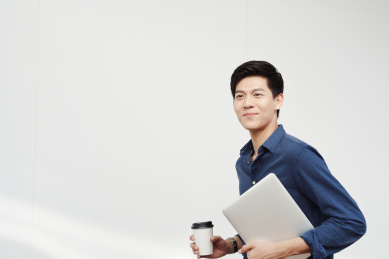 一手抱着笔记本电脑一手拿着咖啡的商务男士