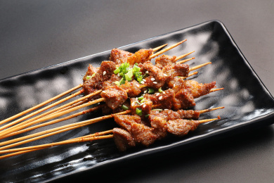 黑色背景上黑色陶盘中的烤肉串
