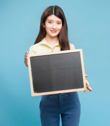  蓝色背景里，拿着小黑板的亚洲美女