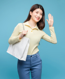 蓝色背景里，拿着购物袋的亚洲美女