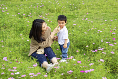 花丛中一个年轻的妈妈跟小男孩在玩耍