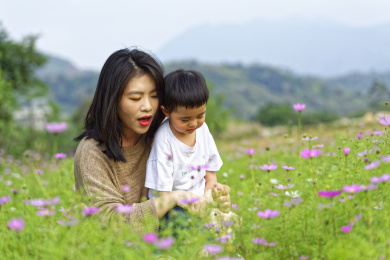 花丛中一个年轻的妈妈跟小男孩在玩耍