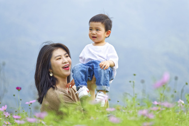 花丛中一个年轻的妈妈抱着小孩玩耍