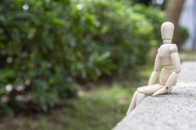 一个木偶孤单地侧坐在岩石上