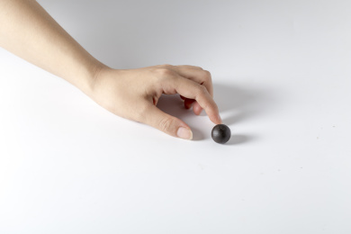 白色背景一只手拿着一颗中成药药丸特写