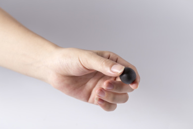 白色背景一只手拿着一颗中成药药丸特写