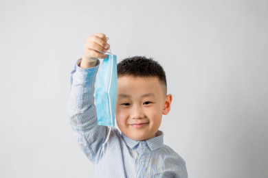 摘下蓝色口罩挥舞的亚洲男孩