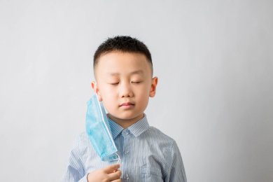 摘下蓝色口罩深呼吸的亚洲男孩