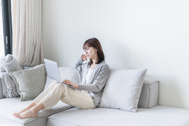 亚洲女生坐在沙发上用电脑办公