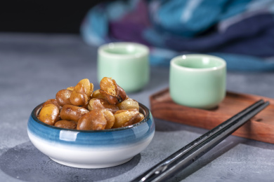 一碟油炸兰花豆特写旁边放有酒壶酒杯茶杯