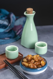 一碟油炸兰花豆特写旁边放有酒壶酒杯茶杯