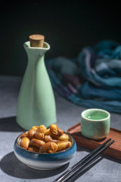 一碟油炸兰花豆特写旁边放有酒壶酒杯茶杯