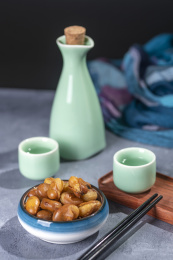 一碟油炸兰花豆特写旁边放有酒壶酒杯茶杯