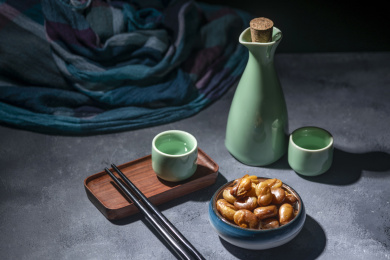 一碟油炸兰花豆特写旁边放有酒壶酒杯茶杯