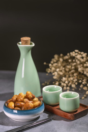一碟油炸兰花豆特写旁边放有酒壶酒杯茶杯