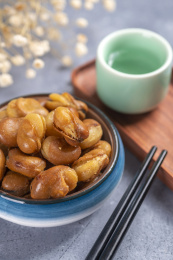 一碟油炸兰花豆特写旁边放有酒壶酒杯茶杯