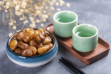 一碟油炸兰花豆特写旁边放有酒壶酒杯茶杯