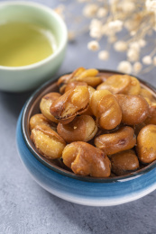 一碟油炸兰花豆特写旁边放有酒壶酒杯茶杯