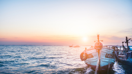 海岸边停靠的一艘蓝色的渔船在夕阳下