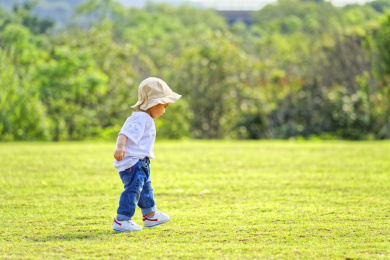 一个戴帽子的小男孩在绿色草地上玩耍