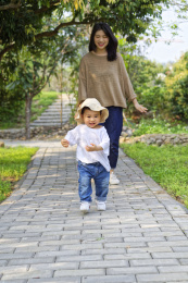 一位年轻妈妈在林荫小道上追赶小男孩