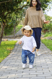一位年轻妈妈在林荫小道上追赶小男孩