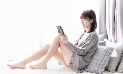 亚洲女性坐在窗边的飘窗上看电子书