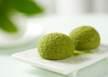 浅色背景上餐具上摆放的抹茶口味大福