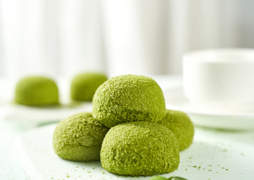 浅色背景上餐具上摆放的抹茶口味大福