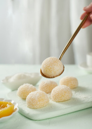 浅色背景上餐具上摆放的黄桃口味大福