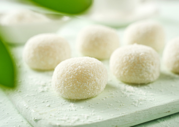 浅色背景上餐具上摆放的椰蓉原味大福