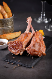 一对法式煎小羊排放在黑色岩石盘上