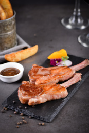 一对法式煎小羊排放在黑色岩石盘上