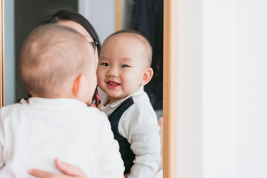 在卧室对着镜子玩耍的婴儿