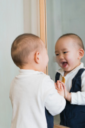 在卧室对着镜子玩耍的婴儿