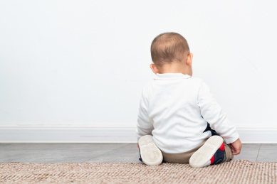 跪坐在地板上的亚裔婴儿背影