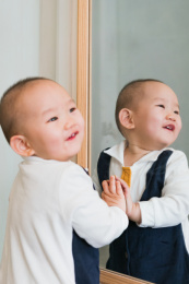 在卧室对着镜子玩耍的婴儿