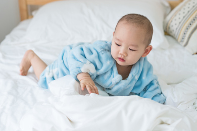 卧室里穿着睡衣的婴儿在床上玩耍爬行