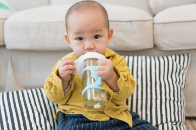 房间里坐在地毯上吃奶的婴儿