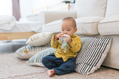 房间里坐在地毯上吃奶的婴儿