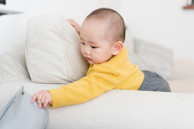 在房间沙发上玩耍的亚裔婴儿