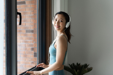 一位年轻的亚洲女性在窗边听音乐