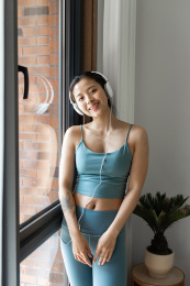 一位年轻的亚洲女性在窗边听音乐