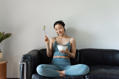一位年轻的亚洲女性在客厅吃健康的蔬菜沙拉