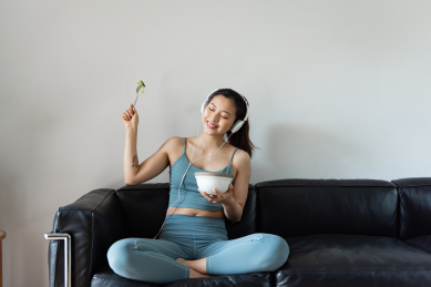 一位年轻的亚洲女性在客厅吃健康的蔬菜沙拉
