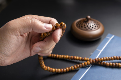 黑背景前手捻佛珠特写