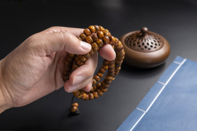 黑背景前手捻佛珠特写