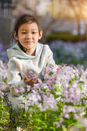 女孩蹲在开满二月蓝的草地上玩耍